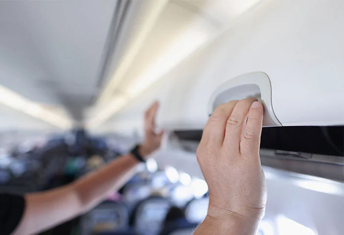 Man stänger handbagagehyllan i kabinen på ett flygplan