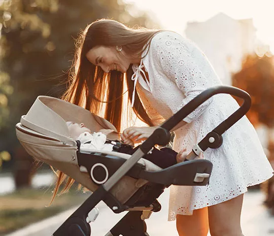 Mamma tittar på ett spädbarn i en resevagn